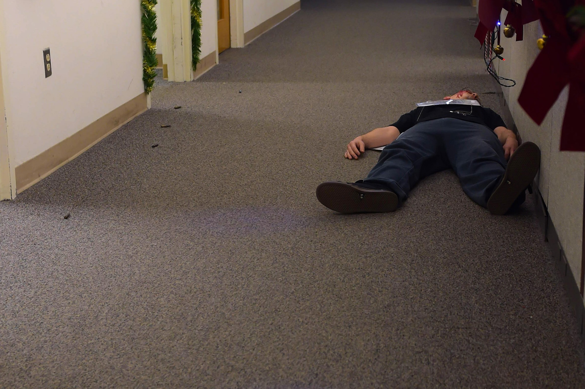 An individual, posing as a casualty, lays in front of the 633rd Civil Engineer Squadron customer service desk during an active shooter exercise at Joint Base Langley-Eustis, Va., Dec. 15, 2016. During the exercise, four individuals were confirmed deceased and six injured after a disgruntled customer attacked personnel in the building. (U.S. Air Force photo by Senior Airman Kimberly Nagle)