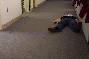 An individual, posing as a casualty, lays in front of the 633rd Civil Engineer Squadron customer service desk during an active shooter exercise at Joint Base Langley-Eustis, Va., Dec. 15, 2016. During the exercise, four individuals were confirmed deceased and six injured after a disgruntled customer attacked personnel in the building. (U.S. Air Force photo by Senior Airman Kimberly Nagle)