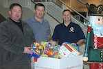 DLA Energy employees and retired Marines, from left to right, Dan Martineau, Richard “Tony” Rabak and Jason Hayungs place new, unwrapped toys in the Toys for Tots drop boxes at Fort Belvoir, Virginia, Dec. 15. 