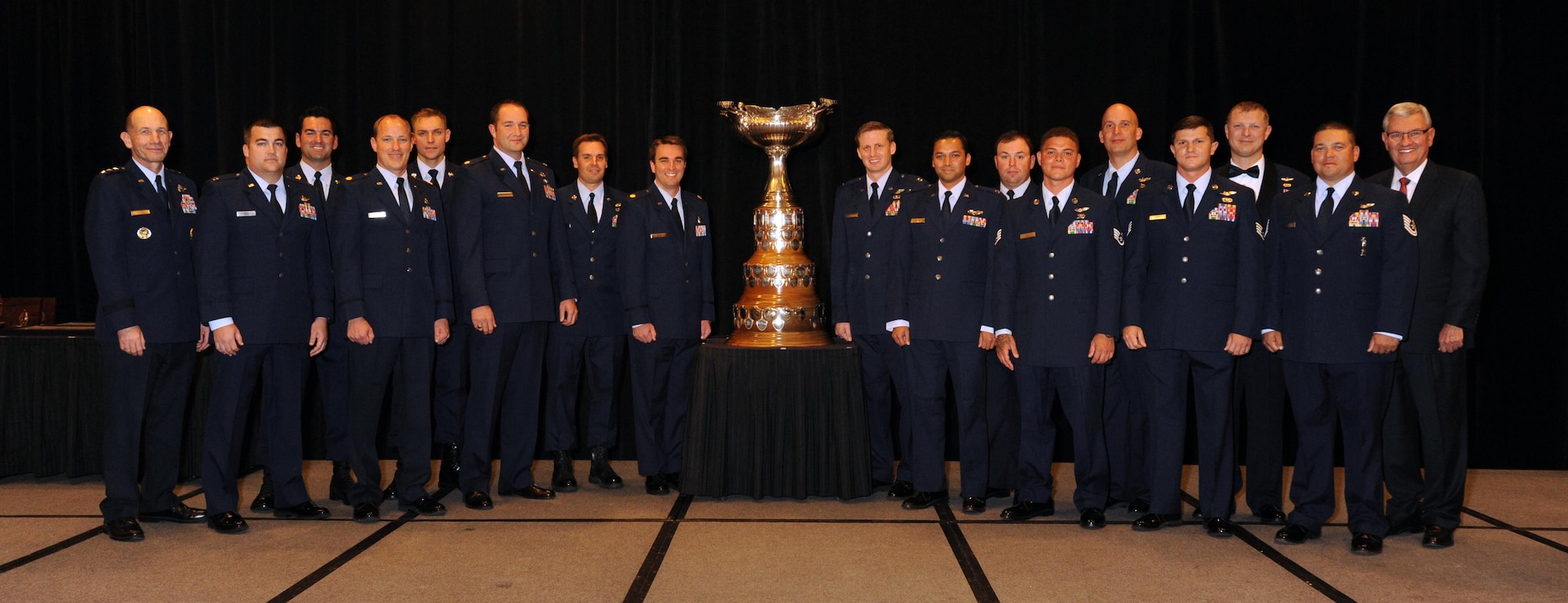 Members of Rooster 73 Flight pose for a group photo after being presented the 2013 Mackay Trophy for the most meritorious flight of the year at the National Aeronautic Association Fall Awards Dinner Nov. 5, 2014 in Arlington, Va. Three 920th Rescue Wing pararescuemen were part of the mission (from left to right, back row, to the left of the trophy), Tech. Sgt. Dan Warren, Staff Sgt. Lee Von Hack-Prestinary and Tech. Sgt. Jason Broline. The crew earned the award for their heroic efforts to safely evacuate American citizens and provide medical care to the passengers who were critically injured when their CV-22 Osprey came under heavy enemy fire during the mission. (Courtesy photo) 