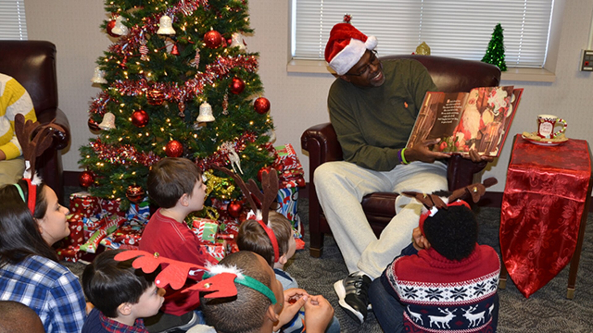 Defense Logistics Agency Aviation Customer Operations Mapping employee, Kevin Bettis, division chief, reads to children of Mapping employees Dec. 20, 2016. The children came to the installation to make Christmas cards to attach to gifts purchased by employees. The gifts are being donated to the children who are patients at Children’s Hospital of Richmond at Virginia Commonwealth University.