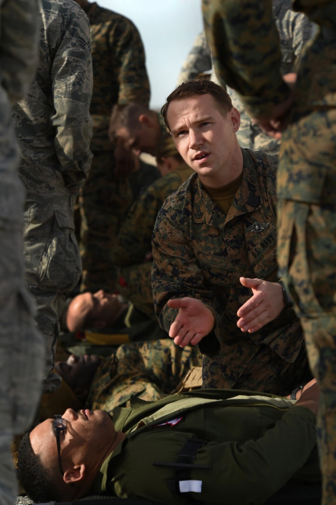 A Sailor with the 15th Marine Expeditionary Unit instructs Airmen and Marines on self-aid and buddy care Dec. 12, 2016, at Desert Rock Airport, Nev. Creech Airmen applied the SABC during a simulated mass casualty event while role playing in a non-combatant evacuation operation scenario. (U.S. Air Force photo by Airman 1st Class James Thompson) 