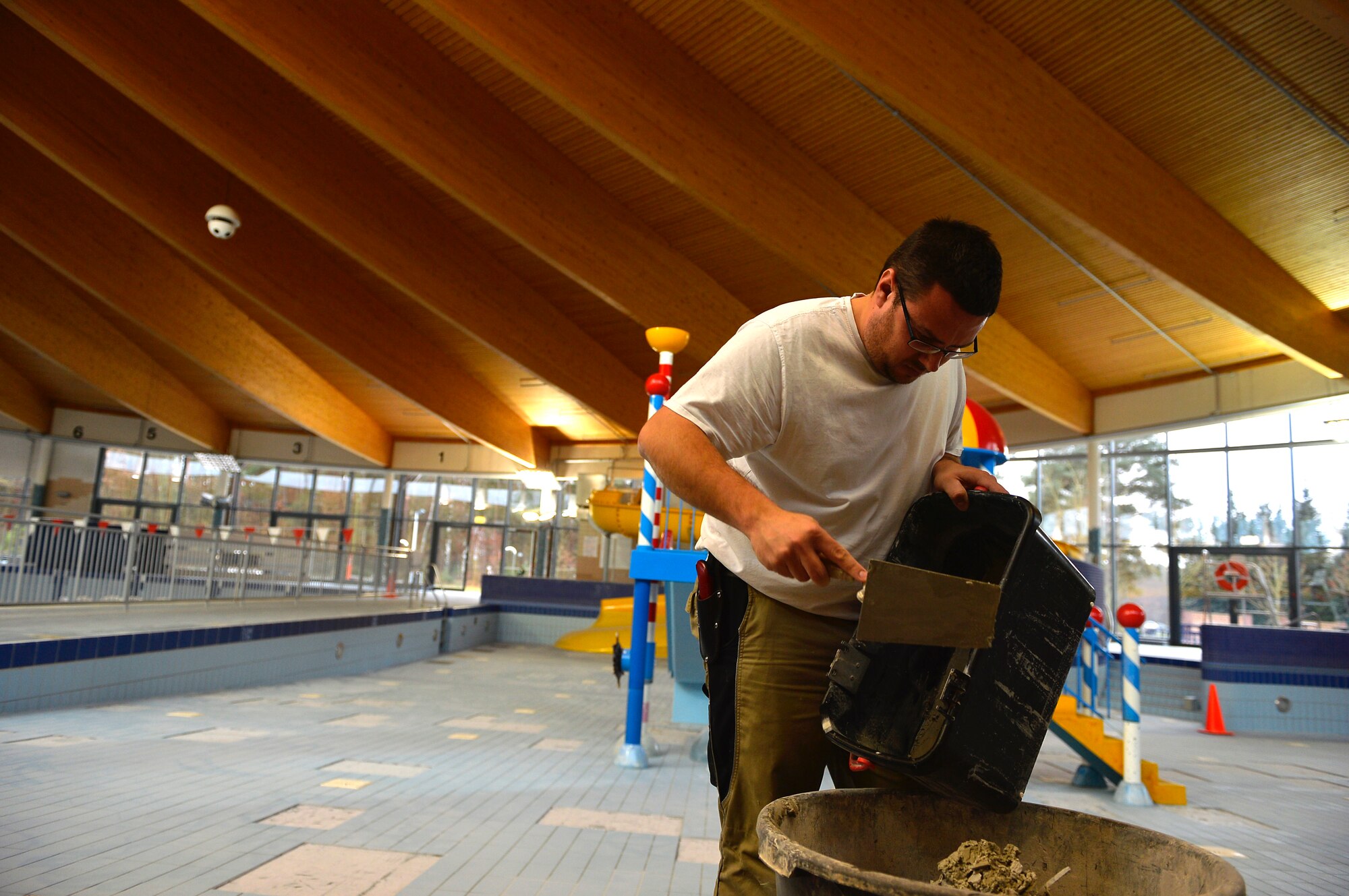 Christian Kampa, 786th Civil Engineer Squadron structural maintainer, dumps old mortar into a bin while doing maintenance work at the aquatic center on Ramstein Air Base, Germany, Dec. 15, 2016. Maintenance work included replacing old tiles in the pools, redoing grout work, and replacing old slides in the children’s area. (U.S. Air Force photo Airman 1st Class Joshua Magbanua)