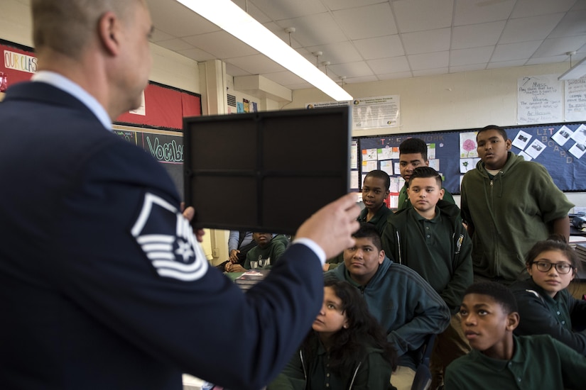 Master Sgt. David Gray, 113th Air National Guard security forces member, shows Charles Carroll Middle School students a photo during their Career and Technical Education Fair in New Carrollton, Md., Dec. 21, 2016. Gray had photos of him previously in the Army, on deployment and shaking hands with the Chairman of the Joint Chiefs of Staff Gen. Colin Powell. (U.S. Air Force photo by Senior Airman Philip Bryant)