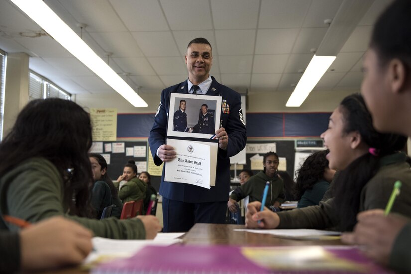 Master Sgt. David Gray, 113th Air National Guard security forces member, shows Charles Carroll Middle School students a photo from when he worked with the Chairman of the Joint Chiefs of Staff Gen. Colin Powell in New Carrollton, Md., Dec. 21, 2016. During a Career and Technical Education Fair, students were briefly introduced to some of the opportunities the U.S. Air Force can present and what it means to be in the Air Force. (U.S. Air Force photo by Senior Airman Philip Bryant)