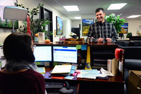 Kevin Younkin, 341st Operations Support Squadron security specialist, talks to Shannon Pea, 341st OSS unit program coordinator in the commander’s support section office Nov. 2, 2016, at Malmstrom Air Force Base, Mont. Younkin is known in the squadron for being friendly and knowledgeable in maintaining communications security. (U.S. Air Force photo/Airman 1st Class Magen M. Reeves)