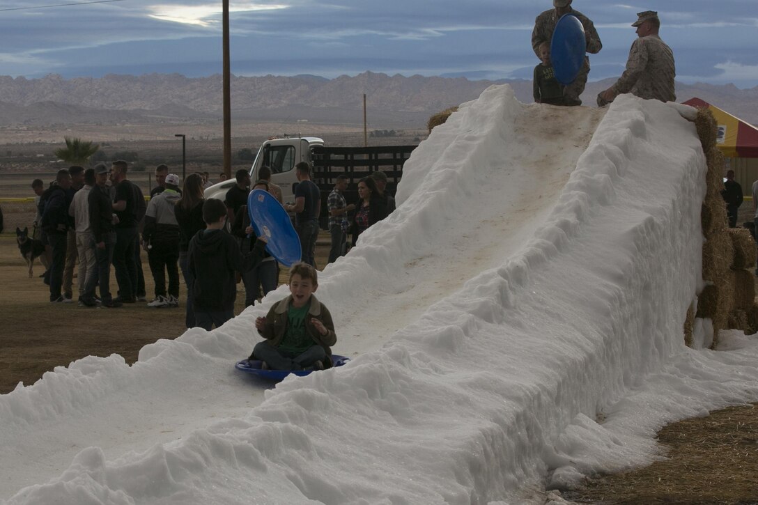 Children slide down a man-made snow hill during the 1st Battalion, 7th Marine Regiment Family Day at Del Valle Field aboard Marine Corps Air Ground Combat Center Twentynine Palms, Calif., Dec. 15, 2016. (Official Marine Corps photo by Cpl. Thomas Mudd/Released)