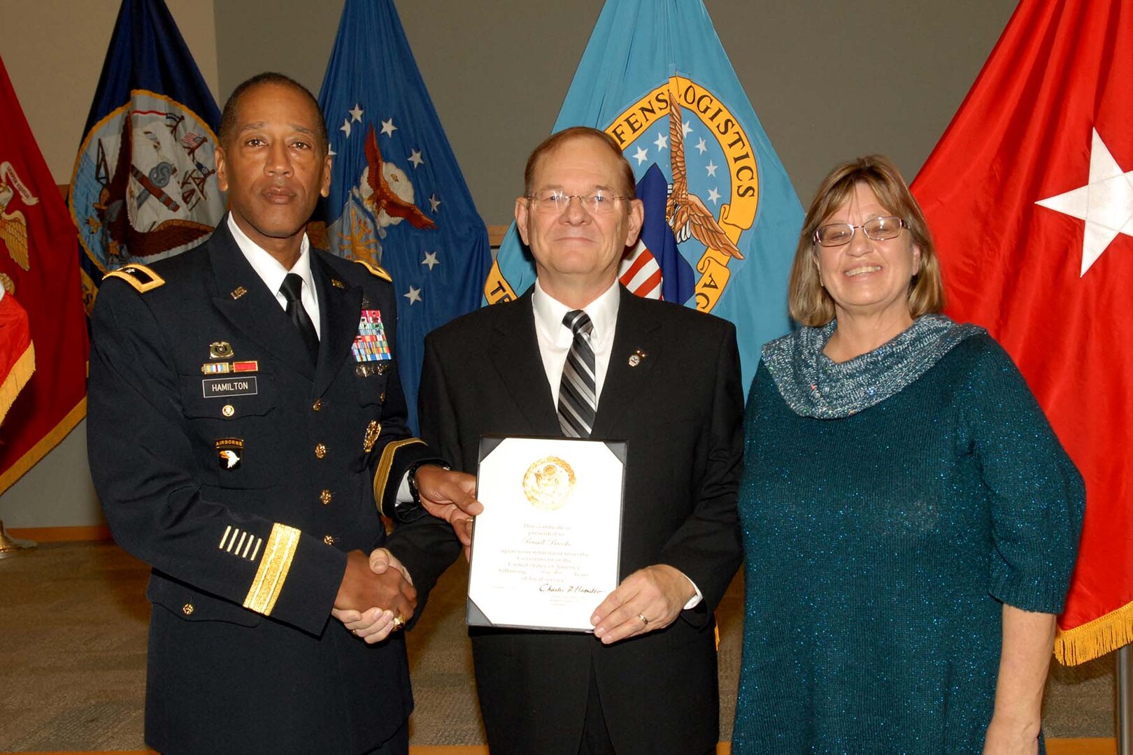 Army Brig. Gen. Charles Hamilton, DLA Troop Support commander, presents Russ Brooks, Subsistence field representative, with a certificate of retirement during a ceremony Dec. 15. Brooks was accompanied by his wife Denise, whom he thanked for standing beside him during his career.