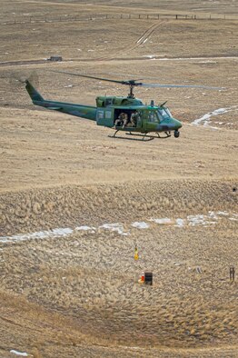 Staff Sgt. Travis Akerson, 37th Helicopter Squadron flight engineer, guides down a hoist to a training target 50 feet below the helicopter during search and rescue training at F.E. Warren Air Force Base, Wyo., Dec. 16. 2016. The 37th HS assists local civilian law enforcement with with SAR operations and airlift medical evacuations in Wyoming, Colorado and Nebraska. (U.S. Air Force photo by Staff Sgt. Christopher Ruano)