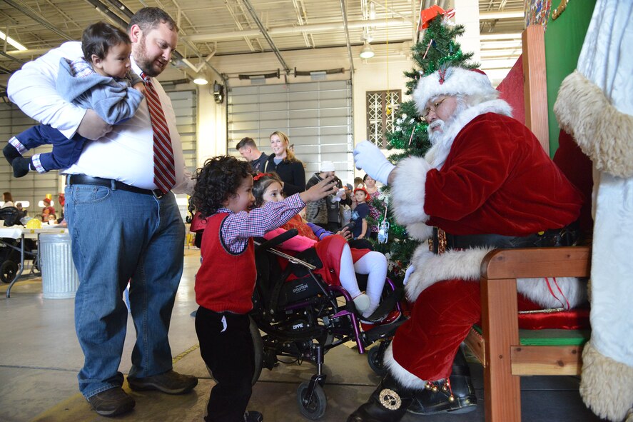 Santa Claus visits with children at Operation Holiday Cheer, one of Kirtland's biggest charitable events of the year. The event, hosted annually by the Kirtland Air Force Base Fire Department, delivered more than 800 new, high-quality toys to children Dec. 14.  More than 1,700 members of the community received a full holiday meal, with turkey, enchiladas, posole, mashed potatoes and desserts. 