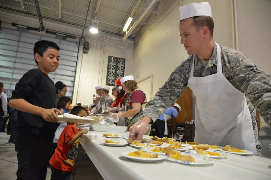 A volunteer from Kirtland serves dinner to a member of the community at Operation Holiday Cheer, one of Kirtland's biggest charitable events of the year. The event, hosted annually by the Kirtland Air Force Base Fire Department, delivered more than 800 new, high-quality toys to children Dec. 14.  More than 1,700 members of the community received a full holiday meal, with turkey, enchiladas, posole, mashed potatoes and desserts. 