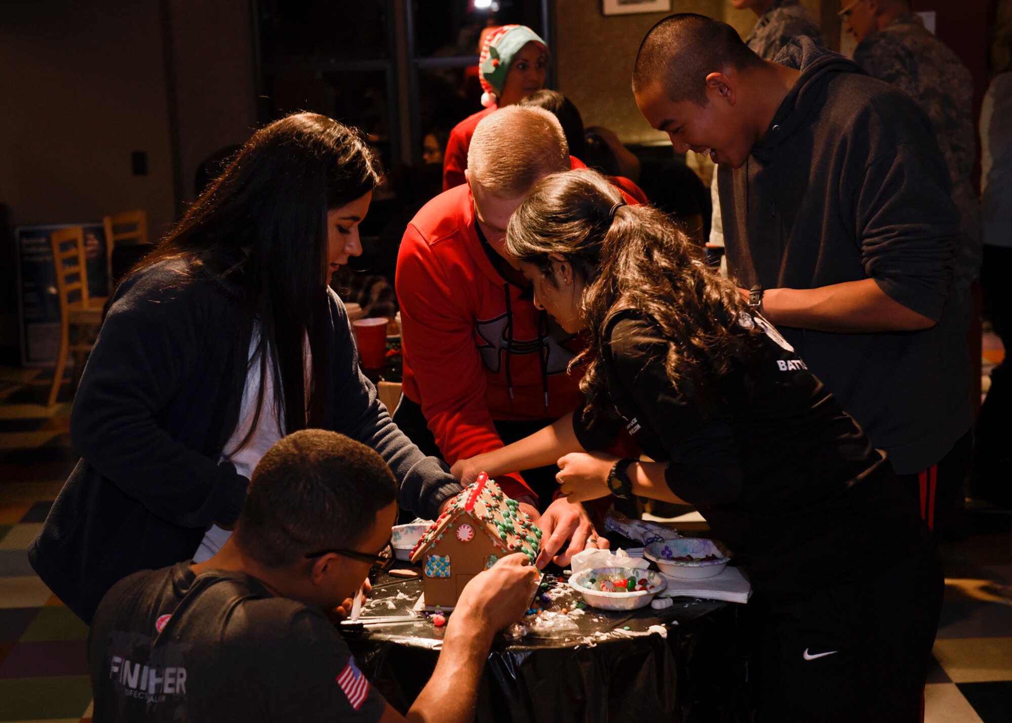 PETERSON AIR FORCE BASE, Colo. – A team of Airmen from Schriever Air Force Base, Colo., strategically place candies on an edible holiday treat during the 4th Annual Gingerbread House Building Competition at the Eclipse Cyber Café on Peterson Air Force Base, Colo., Dec. 14, 2016. The Peterson Chapel hosted the event and provided the supplied for the contest. (U.S. Air Force photo by Senior Airman Rose Gudex)