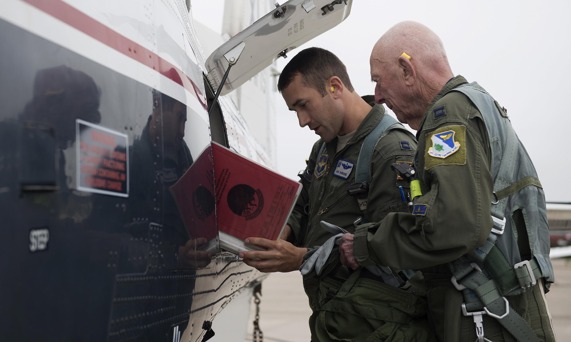 Capt. Steven Parsons, 47th Student Squadron assistant director of operations, and Jerry Yellin, author and retired U.S. Army Air Corps Captain, go over the aircraft forms before their flight in a T-6A Texan II on Laughlin Air Force Base, Texas, Dec. 15, 2016. The aircraft forms include all maintenance performed on the aircraft. (U.S. Air Force photo/Senior Airman Ariel D. Partlow)