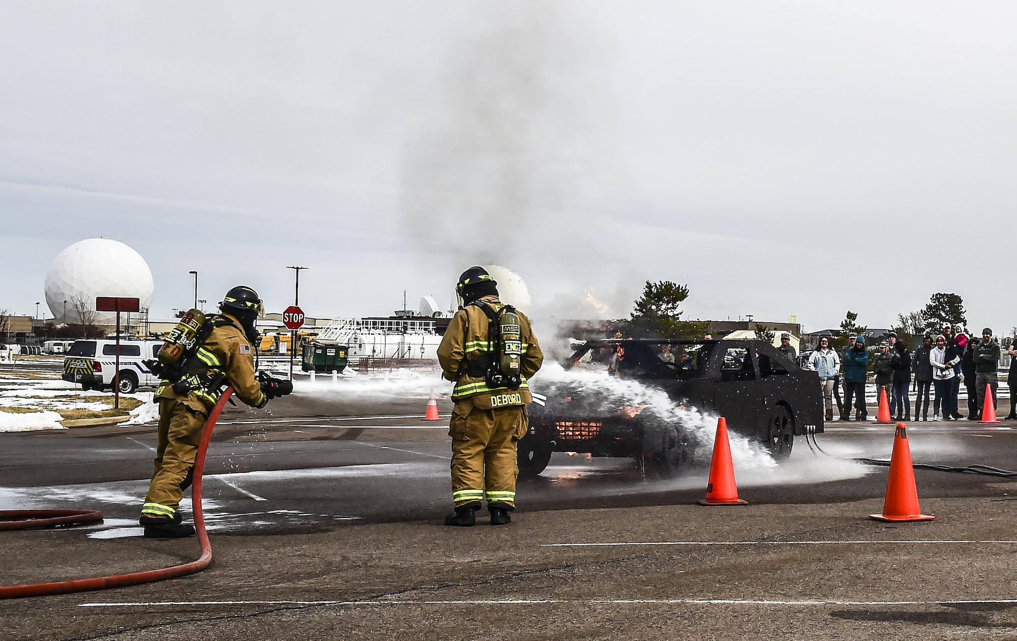 Buckley Firefighters, Andrew Gard and Jason Debord, put out a fire during a live experience at Team Buckley Spouse and Family Day at the Base Chapel on Buckley AFB, Colo., Dec. 22, 2016. The event consisted of families given access to see the 460th Space Wing mission up close, with demonstrations from the operators, Defenders, and firefighters. (U.S. Air Force photo by Tech. Sgt. Nicholas Rau/Released)