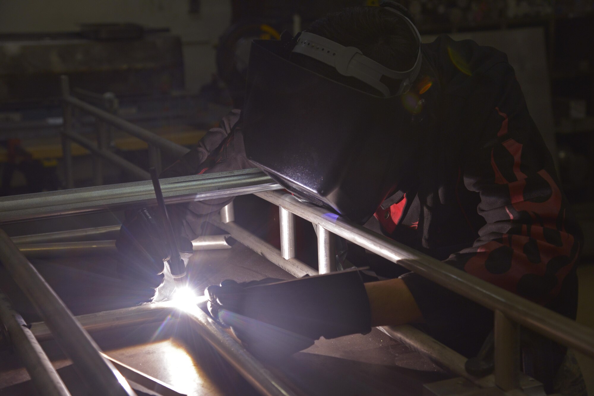 Airman 1st Class Bryce Bibbee, 374th Maintenance Squadron metal technology apprentice, welds two tubes together at Yokota Air Base, Japan, Dec. 20, 2016. In addition to building the life support equipment racks, the squadron is building parachute racks for the C-130J Hercules. (U.S. Air Force photo by Staff Sgt. David Owsianka)