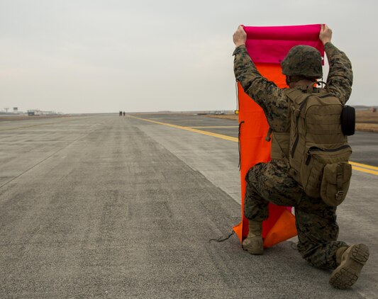 A U.S. Marine with Marine Air Control Squadron 4 Detachment Bravo, Marine Air Traffic Control Mobile Team (MMT), lines up the VS-17 platform with the base Marine while establishing an expeditionary airfield during aircraft landing zone training at Marine Corps Air Station Iwakuni, Japan, Dec. 21, 2016. An MMT team comprises of a base, pace, chase, reference, navigation aid and communication technician who establish a 60-foot-wide and 3,000-foot-long runway in remote locations during combat scenarios, medical evacuations or for humanitarian aid. The MMT Marines conduct this training every three to six months to refine the Marines’ skills, keeping them ready for expeditionary operations while in a garrison environment. (U.S. Marine Corps photo by Lance Cpl. Jacob A. Farbo)