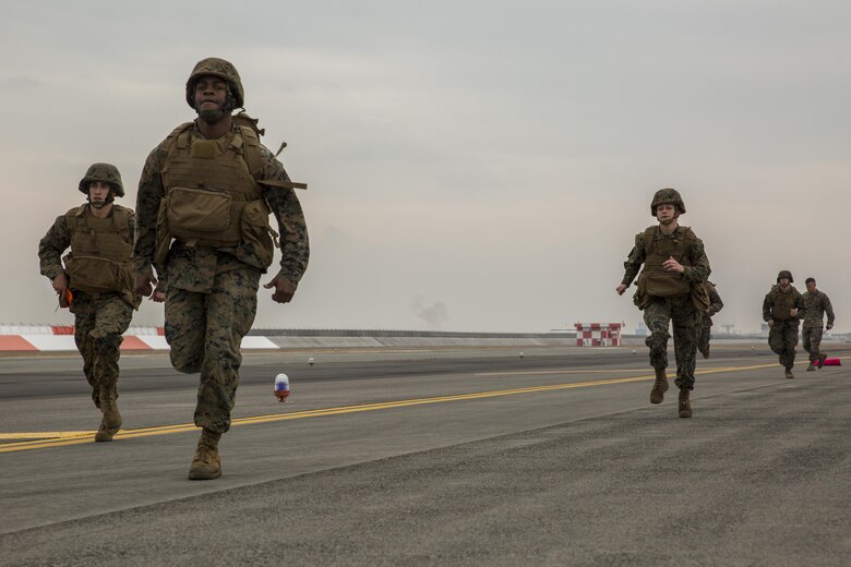 U.S. Marines with Marine Air Control Squadron (MACS) 4 Detachment Bravo, Marine Air Traffic Control Mobile Team (MMT), run to the next 500-foot marker of an expeditionary runway during aircraft landing zone training at Marine Corps Air Station Iwakuni, Japan, Dec. 21, 2016. The training allows the Marines to gain experience, practice constructing an expeditionary airfield, and complete training and readiness requirements. An MMT team comprises of a base, pace, chase, reference, navigation aid and communication technician who establish a runway in remote locations during combat scenarios, medical evacuations or for humanitarian aid. (U.S. Marine Corps photo by Cpl. Aaron Henson)