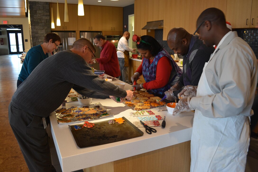From left: Bill Farmer (foreground), Judy Durnin, Tony Acosta, Reggie Burks (at rear counter), Dorothy Russell, Derrick Washington and George Gray of DLA Logistics Operations' Disposal Policy and Compliance Division bake cookies at the USO Metro Warrior and Family Center, Fort Belvoir, Virginia, Dec. 21, 2016.