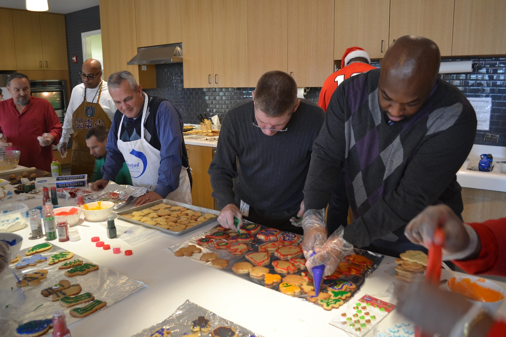 From left: Tony Acosta, Reggie Burks, Mike Johnson, Dennis Ross, Bill Farmer, James Reed (rear, in Santa hat) and Derrick Washington decorate cookies to be distributed Dec. 24 for the USO's annual Christmas Eve 'cookie run,' Fort Belvoir, Virginia, Dec. 21, 2016.