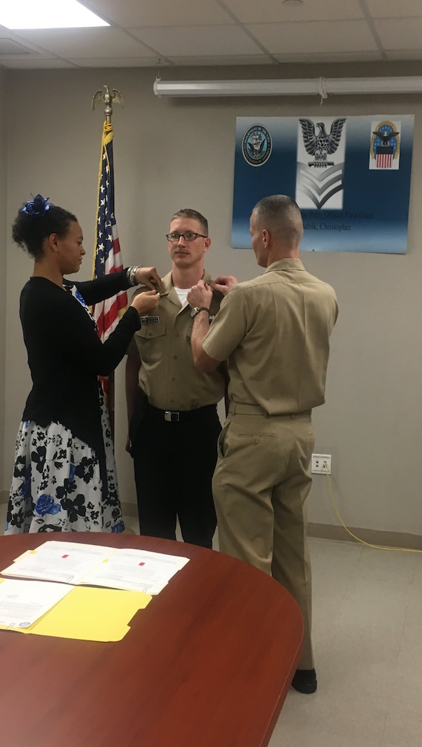 The collar insignia of newly-promoted Navy Petty Officer 1st Class Christopher Szkaradnik is pinned by his wife Brittany and Navy Capt. Harry Thetford, commander, DLA Distribution Norfolk, Va.