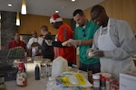 From left: Tony Acosta, Reggie Burks, Bill Farmer, James Reed, Mike Johnson and George Gray prepare the ingredients for cookies the team made from scratch Dec. 21, 2016, at the USO Warrior and Family Center, Fort Belvoir, Virginia.