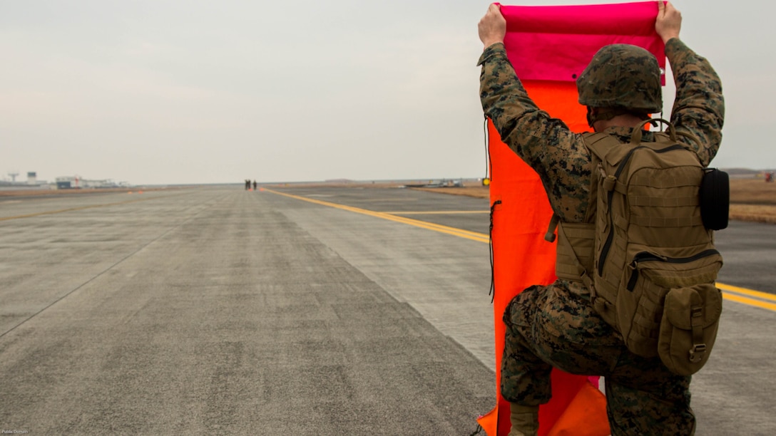 A U.S. Marine with Marine Air Control Squadron 4 Detachment Bravo, Marine Air Traffic Control Mobile Team, lines up the VS-17 platform with the base Marine while establishing an expeditionary airfield during aircraft landing zone training at Marine Corps Air Station Iwakuni, Japan, Dec. 21, 2016. An MMT team comprises of a base, pace, chase, reference, navigation aid and communication technician who establish a 60-foot-wide and 3,000-foot-long runway in remote locations during combat scenarios, medical evacuations or for humanitarian aid. The MMT Marines conduct this training every three to six months to refine the Marines’ skills, keeping them ready for expeditionary operations while in a garrison environment. 