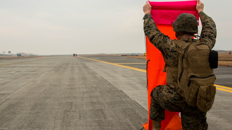 A U.S. Marine with Marine Air Control Squadron 4 Detachment Bravo, Marine Air Traffic Control Mobile Team, lines up the VS-17 platform with the base Marine while establishing an expeditionary airfield during aircraft landing zone training at Marine Corps Air Station Iwakuni, Japan, Dec. 21, 2016. An MMT team comprises of a base, pace, chase, reference, navigation aid and communication technician who establish a 60-foot-wide and 3,000-foot-long runway in remote locations during combat scenarios, medical evacuations or for humanitarian aid. The MMT Marines conduct this training every three to six months to refine the Marines’ skills, keeping them ready for expeditionary operations while in a garrison environment. 