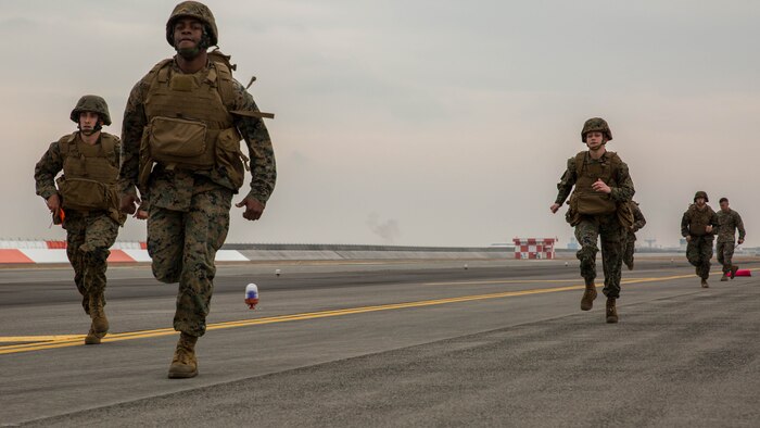 U.S. Marines with Marine Air Control Squadron 4 Detachment Bravo, Marine Air Traffic Control Mobile Team, run to the next 500-foot marker of an expeditionary runway during aircraft landing zone training at Marine Corps Air Station Iwakuni, Japan, Dec. 21, 2016. The training allows the Marines to gain experience, practice constructing an expeditionary airfield, and complete training and readiness requirements. An MMT team comprises of a base, pace, chase, reference, navigation aid and communication technician who establish a runway in remote locations during combat scenarios, medical evacuations or for humanitarian aid. 
