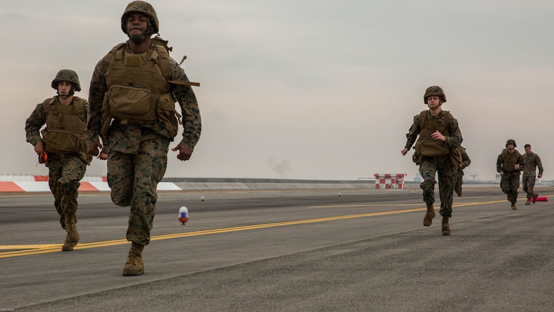 U.S. Marines with Marine Air Control Squadron 4 Detachment Bravo, Marine Air Traffic Control Mobile Team, run to the next 500-foot marker of an expeditionary runway during aircraft landing zone training at Marine Corps Air Station Iwakuni, Japan, Dec. 21, 2016. The training allows the Marines to gain experience, practice constructing an expeditionary airfield, and complete training and readiness requirements. An MMT team comprises of a base, pace, chase, reference, navigation aid and communication technician who establish a runway in remote locations during combat scenarios, medical evacuations or for humanitarian aid. 