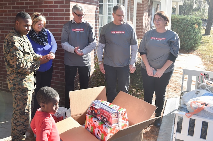 U.S. Marine Staff Sgt. Ruben Barnett, U.S. Naval Consolidated Brig Charleston correctional specialist, and his son, Ruben received gifts from BAE Systems at his new home Dec. 21, 2016. Barnett and his son lost all of their belongings in a house fire the day before Thanksgiving. BAE Systems and Operation Homefront host a campaign called the Joy of Giving where they sponsor a family in need during the holiday season.