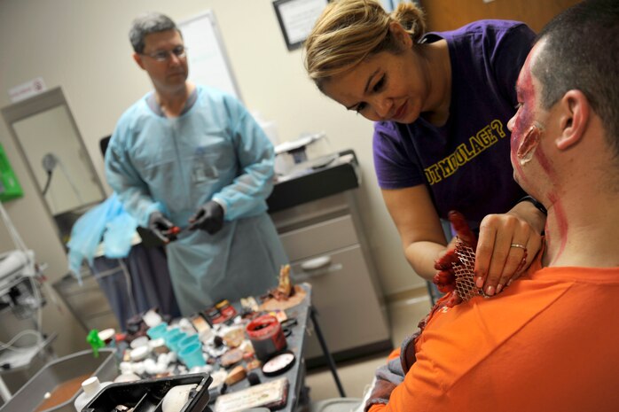 Patrick Miller, 628th Aerospace Medicine Squadron dental hygienist, left, watches on as Master Sgt. Caroline Bunce, 628 AMDS dental hygienist, applies moulage to Technical Sgt. Aaron De L'etoile, 628th Medical Support Squadron medical maintenance NCOIC, in preparation for a mass casualty exercise at Joint Base Charleston, South Carolina, Dec. 21, 2016. Moulage was applied to numerous simulated patients to demonstrate potential injuries caused by explosions. 