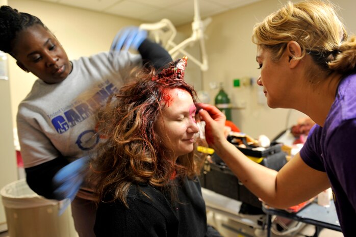 Technical Sgt. Veronica Dickerson, left, and Master Sgt. Caroline Bunce, both 628th Aerospace Medicine Squadron dental hygienists, apply moulage to Master Sgt. Rachel Rapp, 628th Medical Support Squadron medical readiness NCOIC, prior to a mass casualty exercise at Joint Base Charleston, South Carolina, Dec. 21, 2016. Dickerson learned how to apply multiple types of moulage including sucking chest wounds, cuts, shrapnel and bruises. 