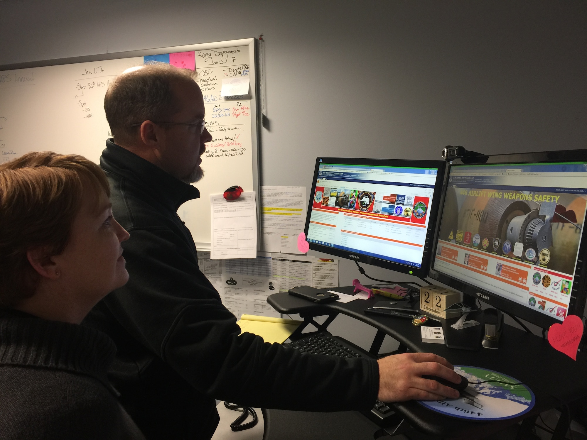 Scott Plocar, 446th Airlift Wing weapons safety manager, shows Angel Cornett, 446th AW Recruiting administrative technician, the SharePoint weapons safety page he designed. The Air Force Reserve Command recently recognized him as the AFRC Outstanding Weapons Safety Civilian of the Year. (U.S. Air Force Reserve photo by Maj. Brooke Davis)