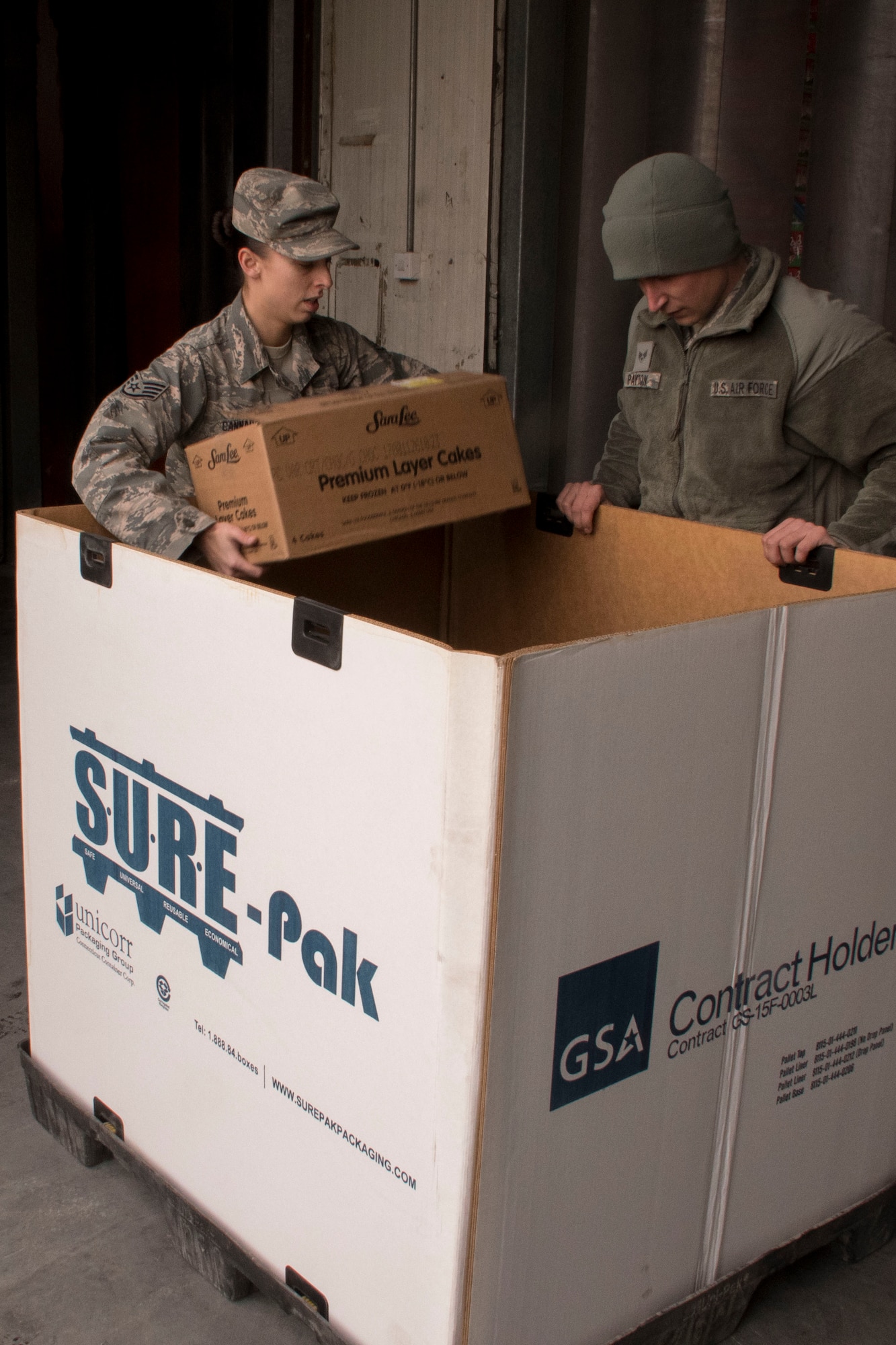 Staff Sgt. Michelle Cannaday, left, and Senior Airman Gavin Payton, right, of the 386th Expeditionary Force Support Squadron stack desserts in a tri-wall Dec. 23, 2016 at an undisclosed location in Southwest Asia. The 386th EFSS loaded several tri-walls with cakes, pies, soft drinks, hot meals, and other items and shipped them to service members in austere locations so that they could celebrate the holidays. (U.S. Air Force photo/Senior Airman Andrew Park)
