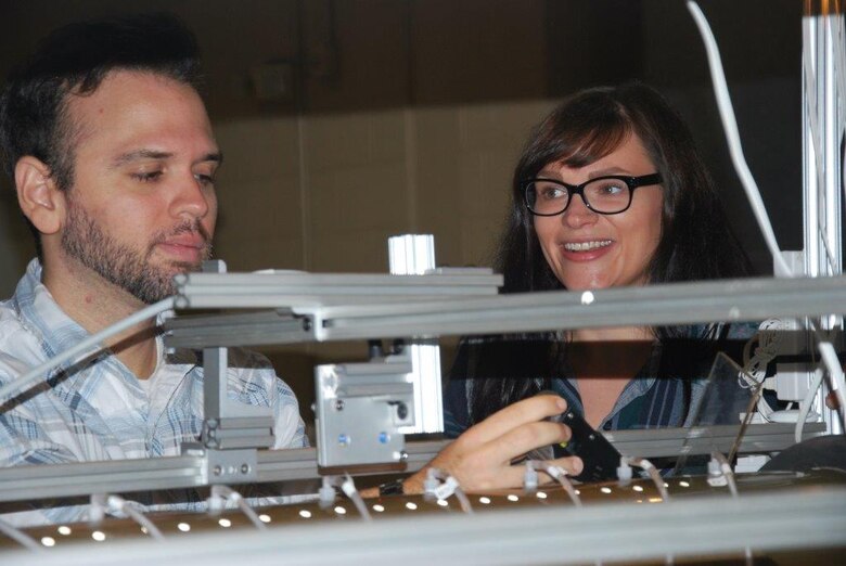 Geotechnical Engineer Axe Montalvo and Huntington District Geologist Erica Medley prepare glacial outwash materials in a cylindrical flume which has pressure transducers located on the top and bottom. Before the test, the laser is adjusted to measure the depth of the sample as material is eroded.