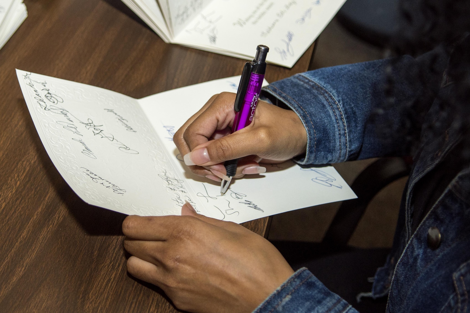 Airman Miranda Loera, 4th Fighter Wing Public Affairs photojournalist, signs holiday cards in Goldsboro, North Carolina, before departing to visit with residents of the North Carolina State Veterans Home in Kinston, North Carolina, Dec. 24, 2016. About 45 volunteers from Seymour Johnson Air Force Base, Goldsboro Elk Lodge #139 and Wayne County passed out handmade goody bags and Christmas cards to the veterans during the holiday visit. (U.S. Air Force photo by Airman Shawna L. Keyes)