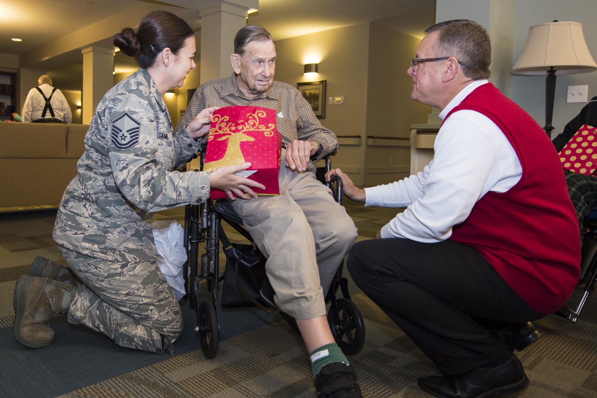 Master Sgt. Jennifer Tamble (left), 4th Equipment Maintenance Squadron NCO in-charge of munitions control, and Doug McGrath (right), Goldsboro Elks Lodge #139 chairman of the veterans committee, visit with a veteran and resident of the North Carolina State Veterans Home, Dec. 24, 2016, in Kinston, North Carolina. More than 90 residents received goody bags and holiday cards from volunteers. (U.S. Air Force photo by Airman Shawna L. Keyes)