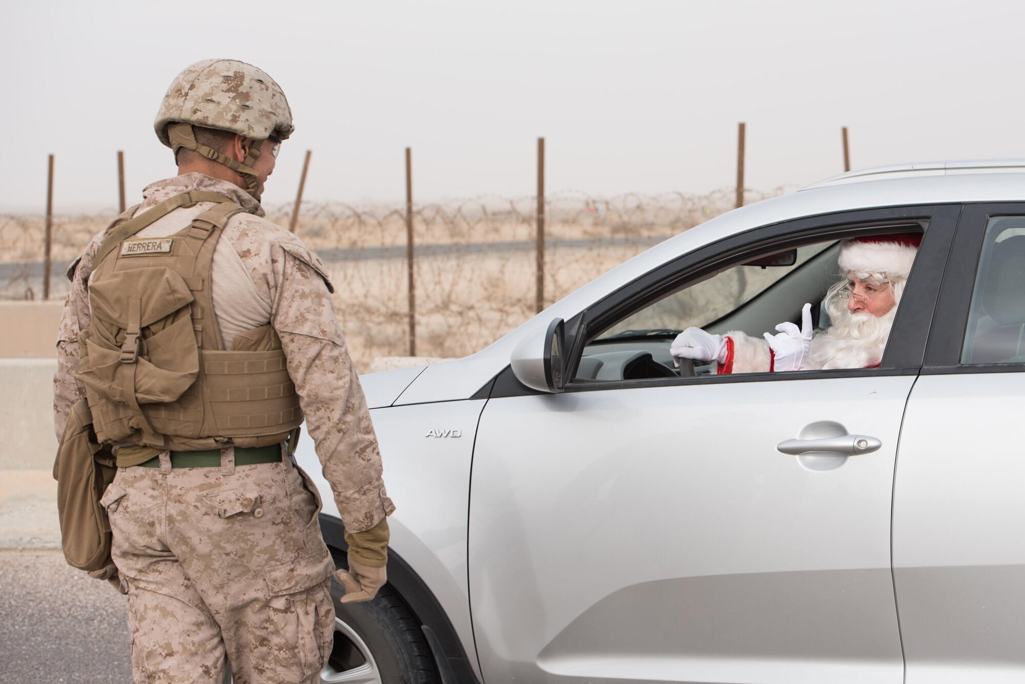 Lance Cpl. Louie Herrera, 407th Expeditionary Security Forces Squadron, checks the military ID card of Santa Clause at an entry control point at the 407th Air Expeditionary Group, Dec. 25, 2015. Herrera said the highlight of his day was a video call with his wife as she opened the Christmas presents he got her. (U.S. Air Force photo by Master Sgt. Benjamin Wilson)