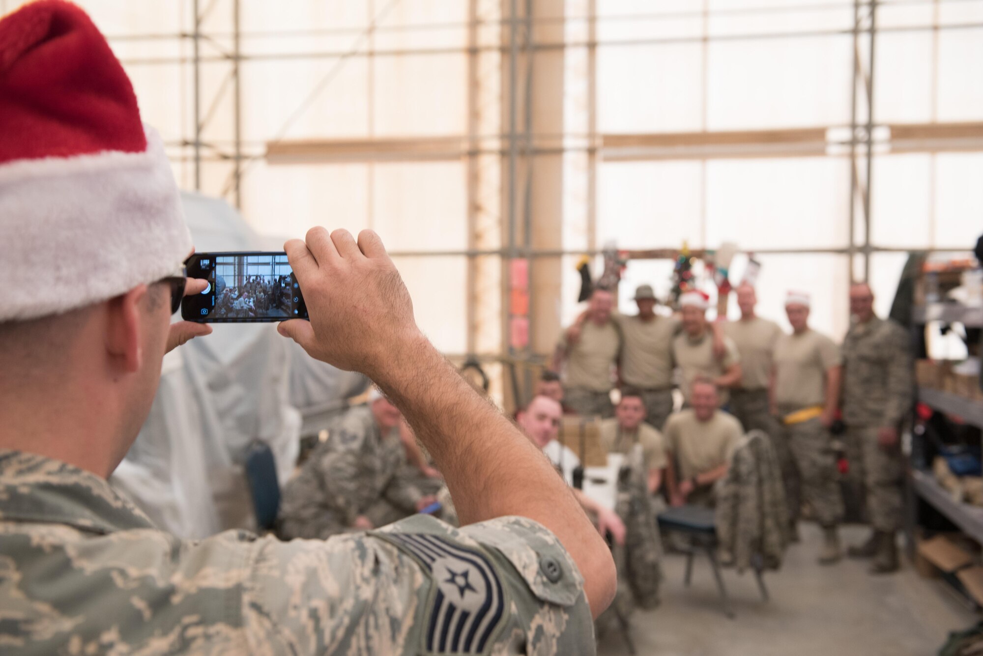 Tech. Sgt. Justin Tierney, 407th Expeditionary Maintenance Squadron, takes a group photo at a holiday party at an undisclosed location in Southwest Asia, Dec. 25, 2016. The deployed Airmen there were working on Christmas Day to enable combat air operations in support of Operation Inherent Resolve. (U.S. Air Force photo/Master Sgt. Benjamin Wilson)