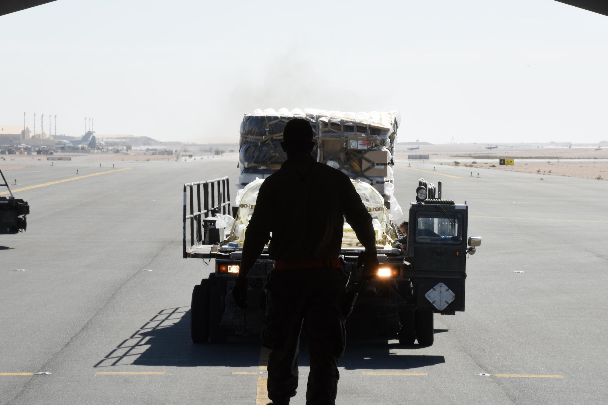A U.S. Air Force Airman with the 8th Expeditionary Air Mobility Squadron guides an Airman driving a Tunner 60K cargo loader at Al Udeid Air Base, Qatar, Dec. 12, 2016. The 8th EAMS expertise in transportation and logistics enable them to inspect, temporarily store and load cargo such as munitions, blood, special operations cargo, hazardous materials, vehicles and medical supplies. (U.S. Air Force photo by Senior Airman Cynthia A. Innocenti)