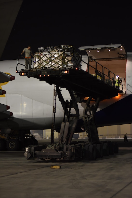 A Tunner 60K cargo loader waits as Airmen with the 8th Expeditionary Air Mobility Squadron offload cargo onto it at Al Udeid Air Base, Qatar, Dec. 24, 2016. The 8th EAMS Airmen work around the clock to ensure cargo is loaded and offloaded efficiently.  (U.S. Air Force photo by Senior Airman Cynthia A. Innocenti)