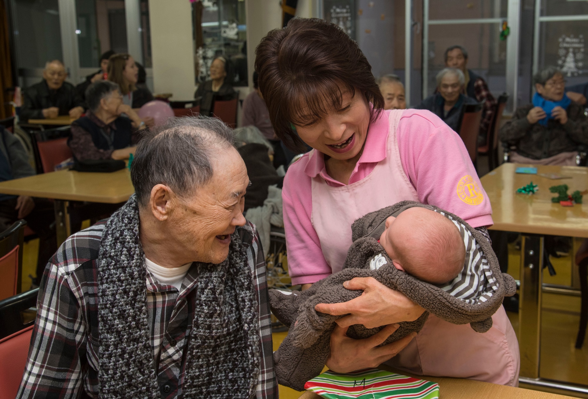 A Japanese elder, left, and Eiko Koiwa, center, a caretaker, smiles at Matthew Joiner, right, son of Master Sgt. James Joiner, a 35th Civil Engineer Squadron explosives ordnance disposal technician, at Harunaoka Old Age Home, Misawa City, Japan, Dec. 22, 2016. Approximately 20 Airmen and their families spent time with members to get them to be active and combat loneliness. As an easy activity, the children brought balloons to bounce back and forth with the Japanese nationals. (U.S. Air Force photo by Airman 1st Class Sadie Colbert)