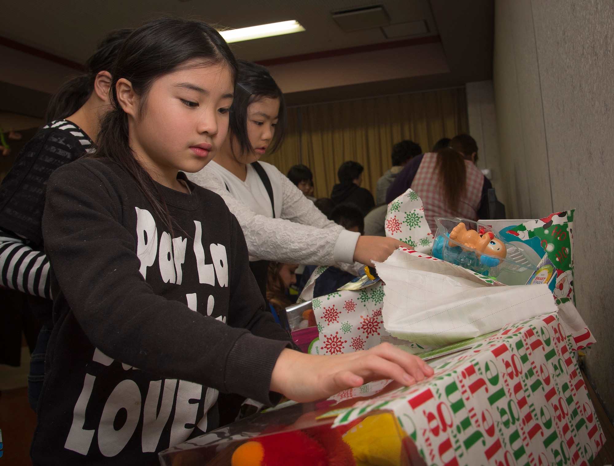 Hoshimi Kohaneo, a Shichinohe Orphange member, unwarps a present received from Misawa Air Force Base Airmen at Shichinohe, Japan, Dec. 23, 2016. The orphanage holds 41 orphans with approximately six caretakers staying overnight to guide them and ensure the group is ready for everyday activities like completing schoolwork. (U.S. Air Force photo by Airman 1st Class Sadie Colbert)