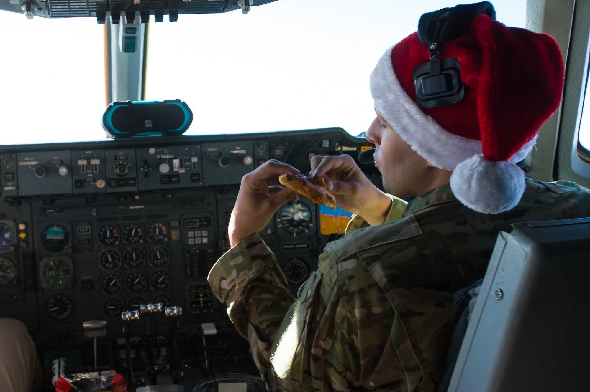 A 380th Air Expeditionary Wing KC-10 Extender pilot, 1st Lt. Andrew, eats reheated pizza during a sortie in support of Combined Joint Task Force-Operation Inherent Resolve over Iraq, Dec. 25, 2016. Crew members used two small ovens to prepare their holiday meal. (U.S. Air Force photo/Senior Airman Tyler Woodward)