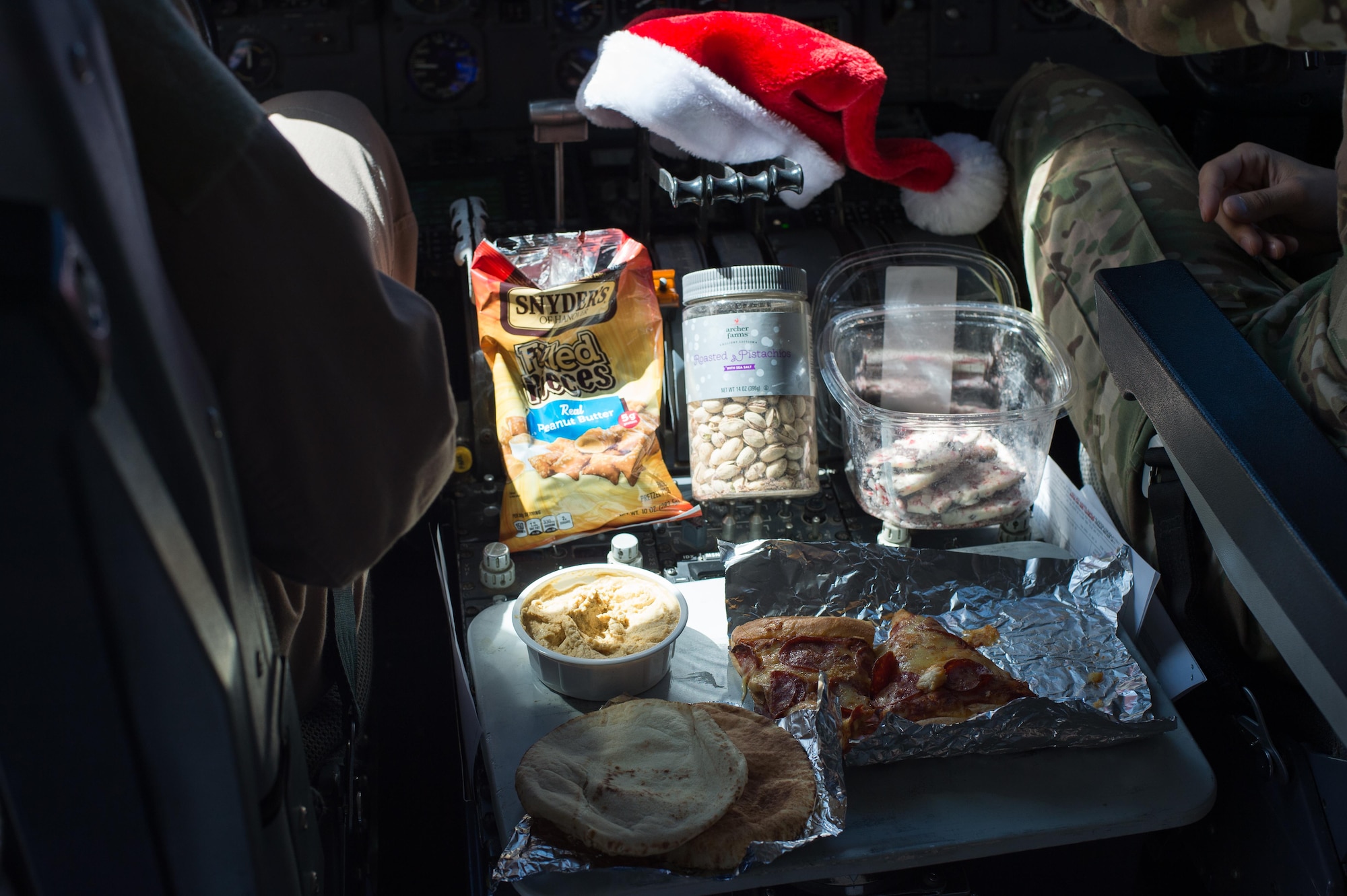 An aircrew eats a holiday meal while flying a sortie in support of Combined Joint Task Force-Operation Inherent Resolve over Iraq, Dec. 25, 2016. During the flight the crew snacked on oven-ready chicken nuggets, pizza and pita bread.  (U.S. Air Force photo/Senior Airman Tyler Woodward)