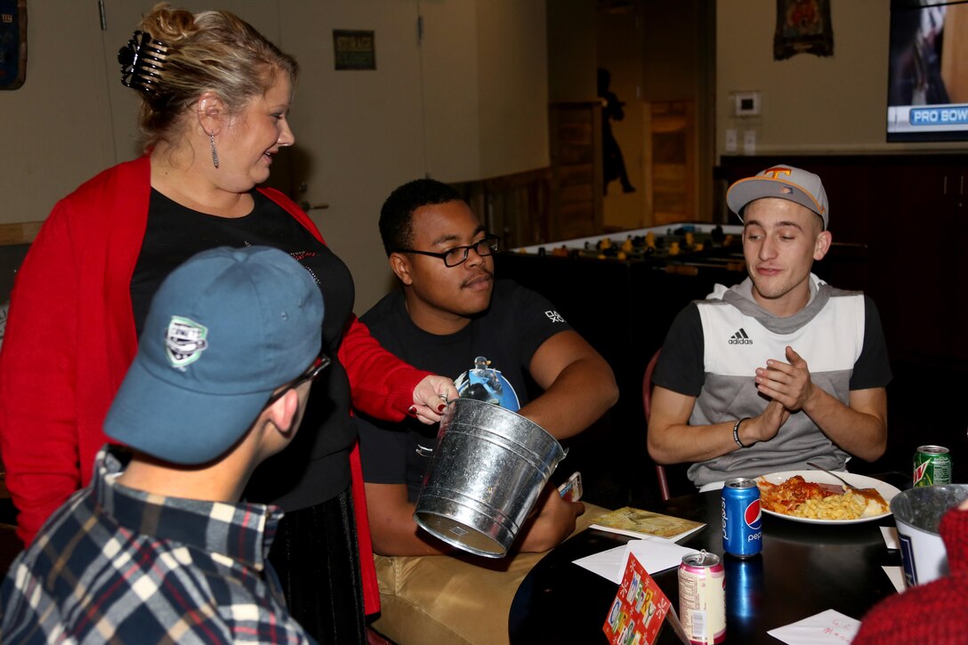 Patty Conway, left, allows service members to pick numbers from a bucket for the white elephant gift exchange during the Single Marine Program’s annual Christmas dinner at the Roadhouse aboard Marine Corps Air Station Cherry Point, N.C., Dec. 25, 2016. The free homemade dinner was open to all single and unaccompanied Marines and Sailors. Activities went on all day at the Roadhouse to include holiday movies, a mega gingerbread house construction and white elephant gift exchange with gifts provided by the SMP. Conway is a recreational assistant with the SMP. (Marine Corps photo by Cpl. Jason Jimenez/ Released)