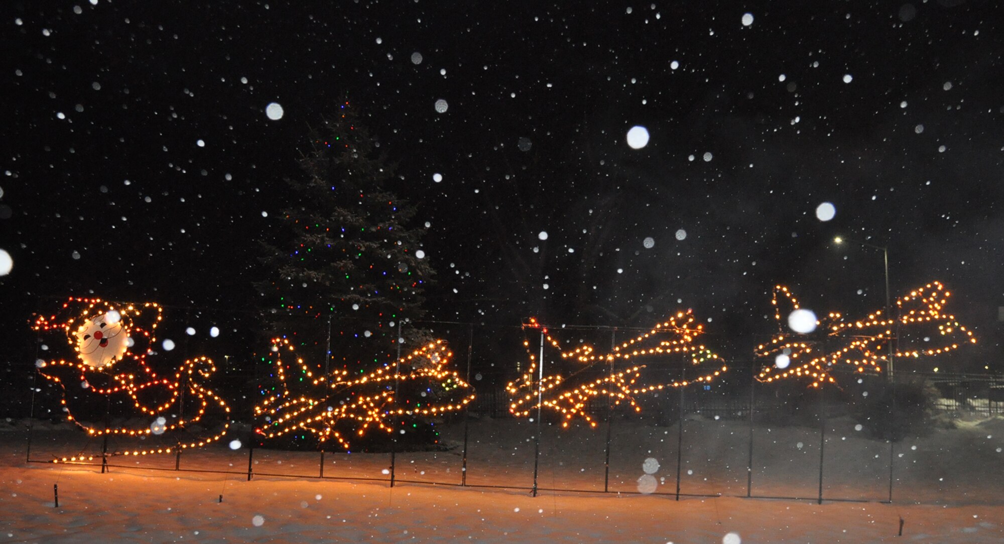 A lighted display of Santa’s sleigh pulled by a trio of C-130 aircraft, along with a massive evergreen tree covered in lights, greet visitors to the installation on a snowy evening here, Dec. 14, 2016. Since the year 2000, the YARS Base Operating Support (BOS) contractors have been charged with maintaining and annually installing the holiday season display. (U.S. Air Force photo/Master Sgt. Bob Barko Jr.)   