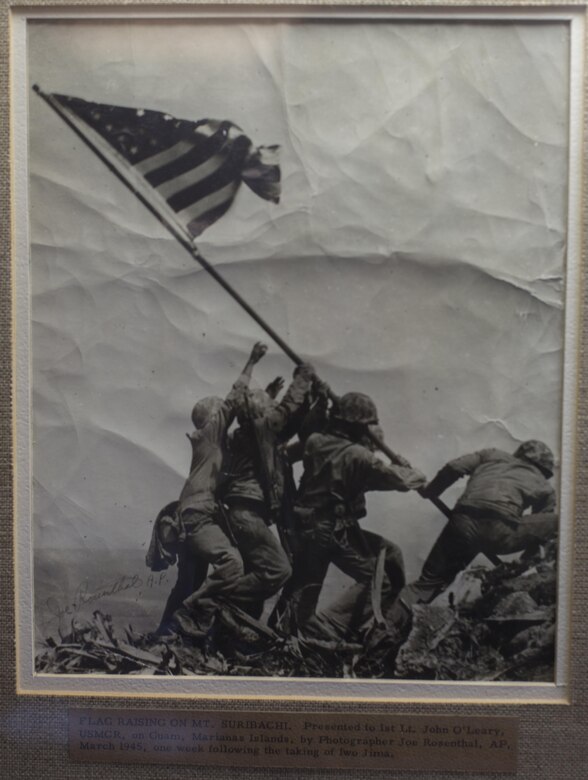 A signed copy of the photo of the second flag-raising on Mt. Suribachi hangs in the room of retired 1st Lt. John J. O’Leary, a Marine veteran of World War II, at the Evergreen Community of Johnson County, Olathe, Kan., Dec. 21, 2016. O’Leary fought on Guam and witnessed the bombardment of Iwo Jima as a member of 3rd Joint Assault Signal Company. He celebrated his 100th birthday on Dec. 23. (U.S. Marine Corps photo by Sgt. Ian Leones)