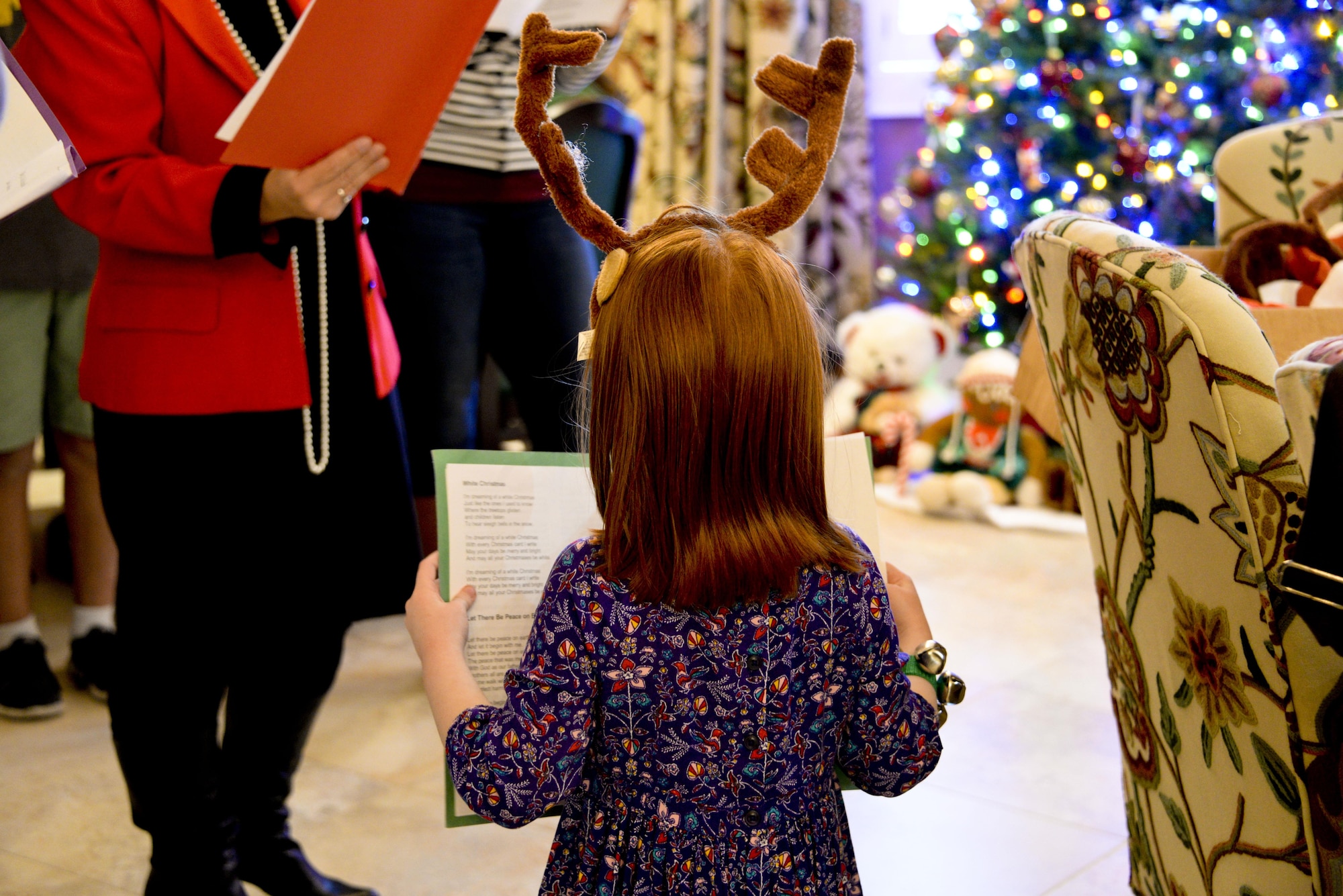 Children of families and employees at the Fisher House sing along as Delia Colvin, Army veteran and international bestselling author, and friend Steven Gary, guitarist and vocalist, perform Christmas carols Dec. 20, 2016 at the Fisher House, Travis Air Force Base, Calif. The Travis Fisher Houses are part of a collection of homes built on military bases to provide a place for families in need to stay without charge when a member is hospitalized. (U.S. Air Force photo/2nd Lt. Sarah Johnson)