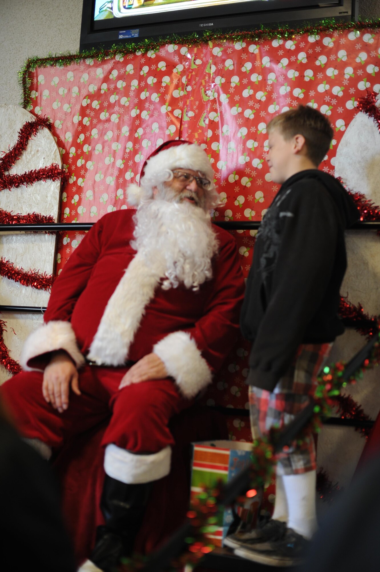 A boy talks with Santa Claus Dec. 20, 2016, at Cedar Lane Elementary School in Olivehurst, California. Marysville Joint Unified School District’s homeless students and their families had the chance to visit with Santa Claus and receive free food and presents. (U.S. Air Force photo by Senior Airman Tara R. Abrahams)